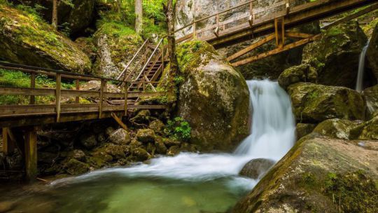 Wasserfall mit Holzstegen und bewachsenen Steinen
