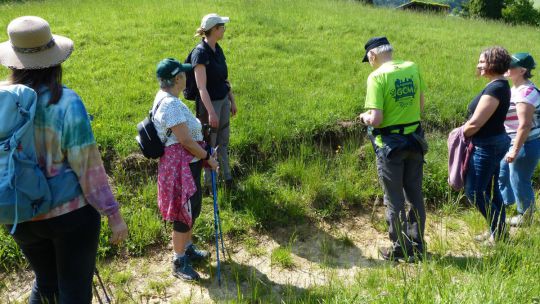 Gruppe von Menschen steht auf einem Feldweg, dahinter eine Wiese