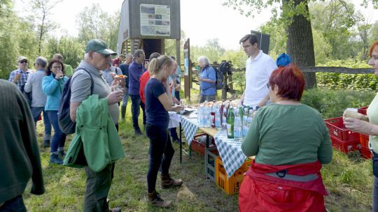 Gruppe von Menschen stehen vor einem Tisch, auf dem Getränke angeboten werden