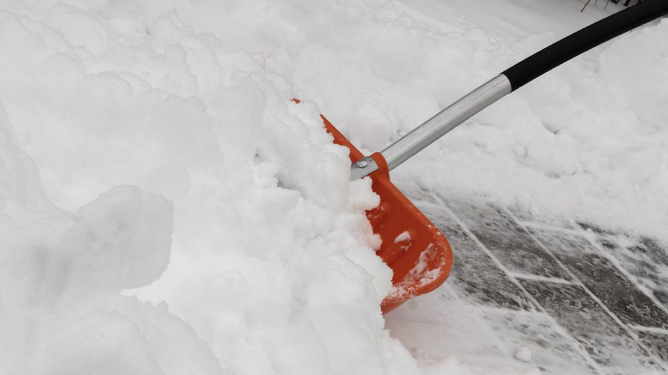 Schnee wird auf einem Weg mit einer Schaufel weggekehrt.