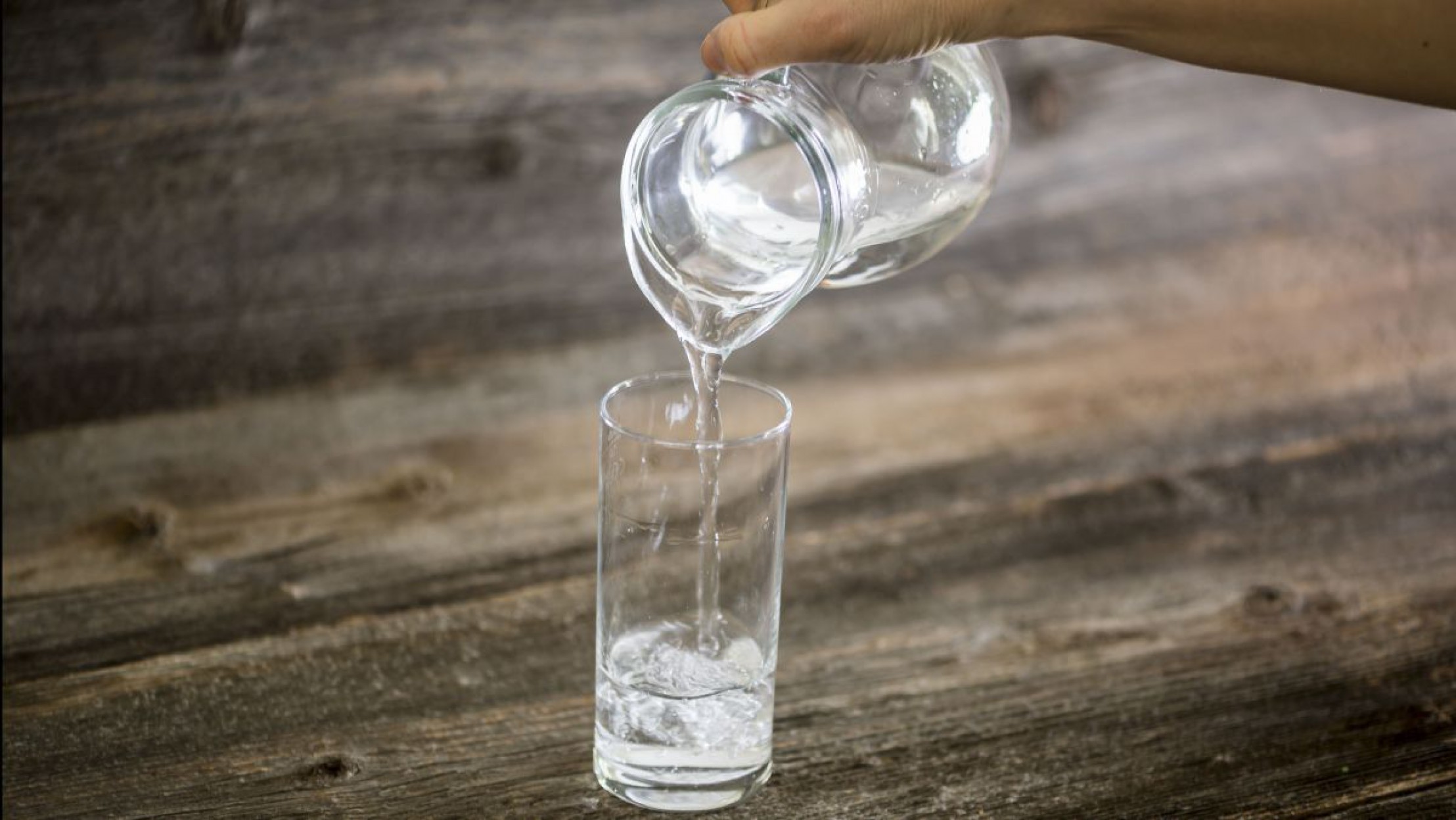 Trinkwasser wird aus einem Klug in ein Glas gef&uuml;llt. 