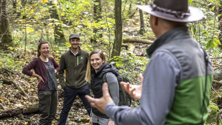 Ein Nationalpark-Ranger f&uuml;hrt zwei Frauen und einen Mann durch den Wald im Thayatal.